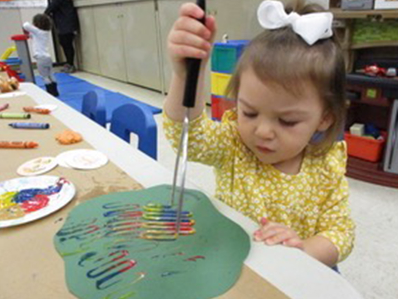 Little girl painting in Tiny Tots Program